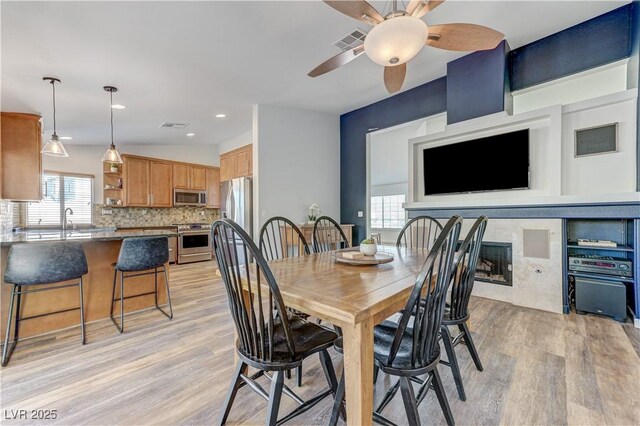 dining space featuring a ceiling fan, visible vents, and light wood-style floors