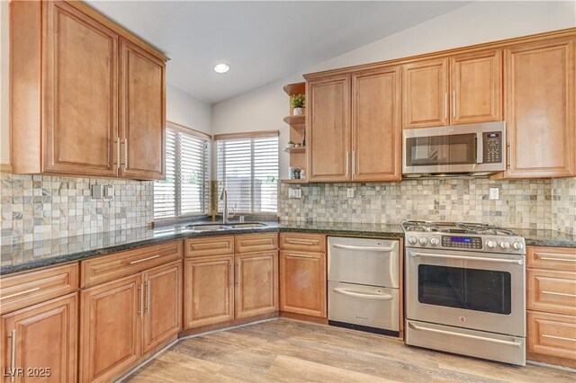 kitchen with appliances with stainless steel finishes, open shelves, a sink, light wood finished floors, and lofted ceiling