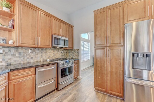 kitchen with open shelves, dark stone countertops, tasteful backsplash, light wood finished floors, and stainless steel appliances