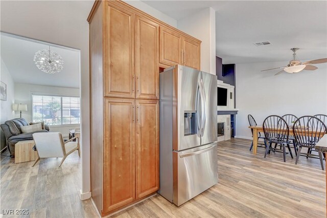 kitchen featuring stainless steel fridge, light wood-style floors, ceiling fan with notable chandelier, and visible vents