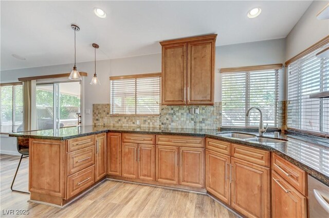 kitchen with a sink, brown cabinetry, light wood finished floors, and a peninsula