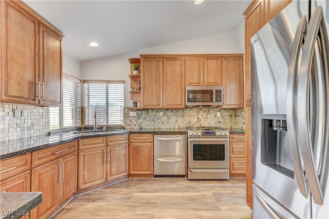 kitchen with stainless steel appliances, a sink, lofted ceiling, and light wood-type flooring