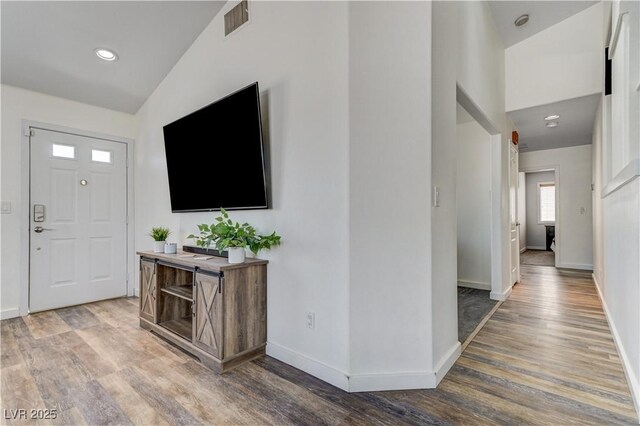 entryway featuring baseboards, vaulted ceiling, recessed lighting, and wood finished floors