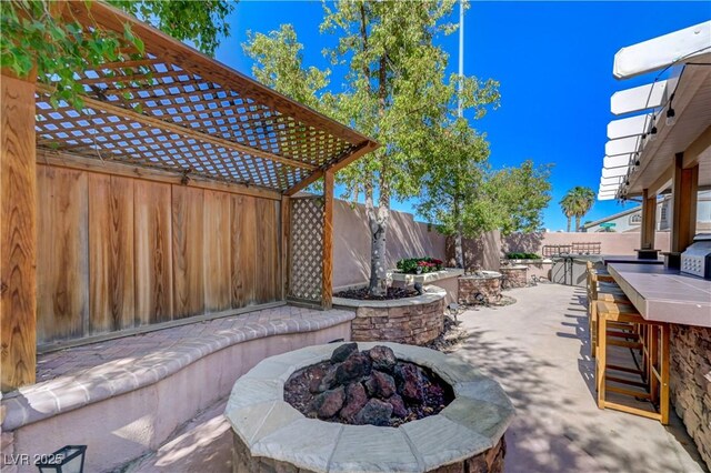 view of patio featuring a fenced backyard, outdoor dry bar, and a fire pit