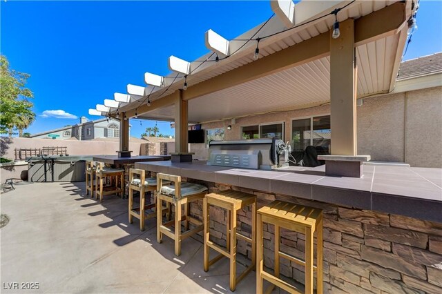 view of patio with fence, outdoor wet bar, and area for grilling