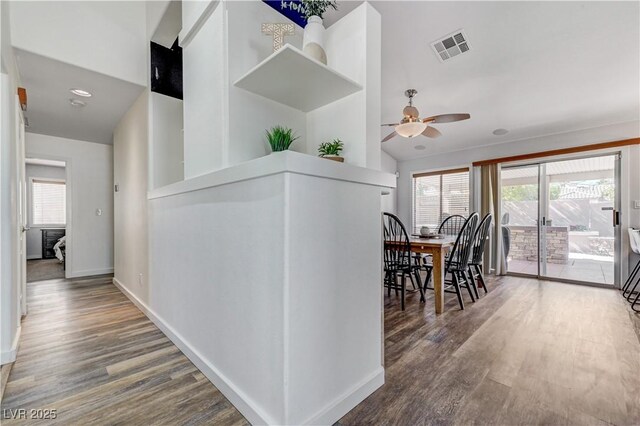 hall featuring visible vents, baseboards, plenty of natural light, and wood finished floors