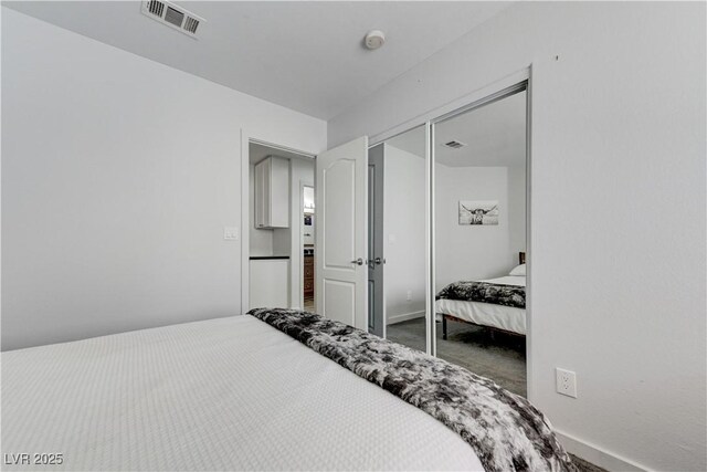 carpeted bedroom featuring baseboards, visible vents, and a closet
