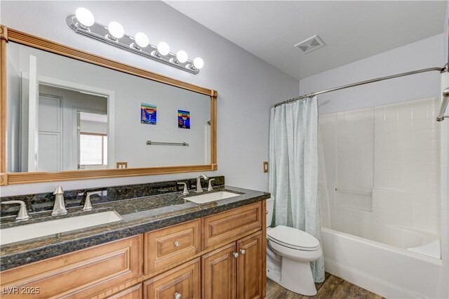 full bathroom with toilet, visible vents, a sink, and wood finished floors