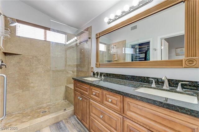 full bath with a sink, vaulted ceiling, tiled shower, and visible vents