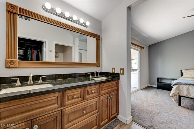 full bathroom with a sink, baseboards, double vanity, and wood finished floors