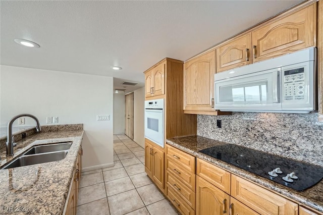 3111 Bel Air Dr Unit 18B, Las Vegas, NV 89109 - kitchen with a sink, light tile patterned floors, stone countertops, light brown cabinets, and white appliances