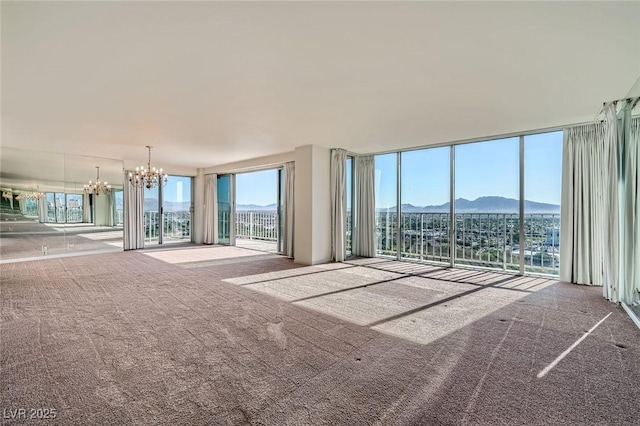 3111 Bel Air Dr Unit 18B, Las Vegas, NV 89109 - unfurnished living room with carpet flooring, a notable chandelier, a mountain view, and expansive windows