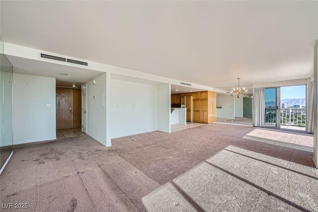 3111 Bel Air Dr Unit 18B, Las Vegas, NV 89109 - unfurnished living room with a chandelier, baseboards, visible vents, and light carpet