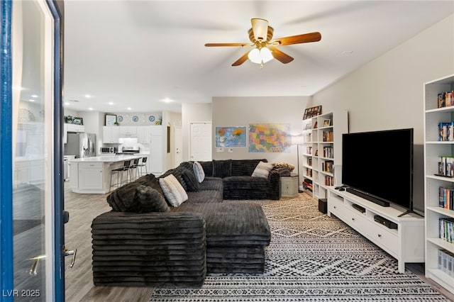 living room with a ceiling fan and light wood finished floors