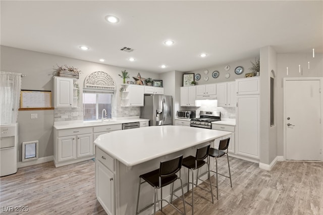 kitchen featuring a breakfast bar area, stainless steel appliances, tasteful backsplash, and light wood-style floors