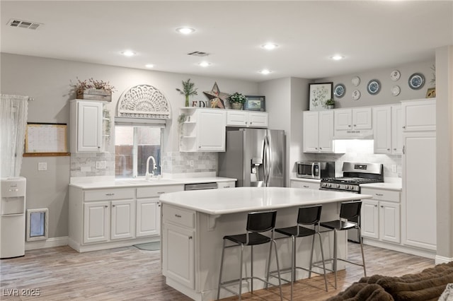 kitchen with a breakfast bar area, stainless steel appliances, visible vents, and a sink