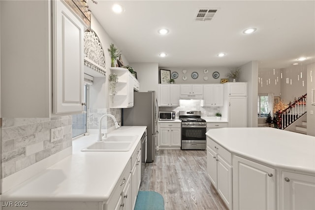 kitchen featuring white cabinets, backsplash, stainless steel appliances, and a sink