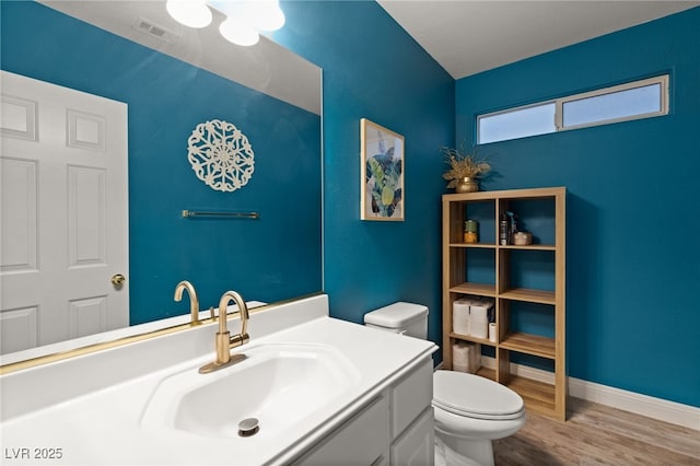 bathroom featuring toilet, wood finished floors, visible vents, baseboards, and vanity