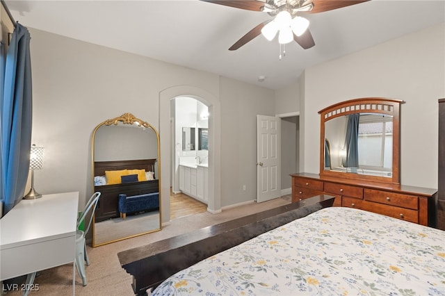 bedroom featuring ceiling fan, ensuite bath, baseboards, and arched walkways