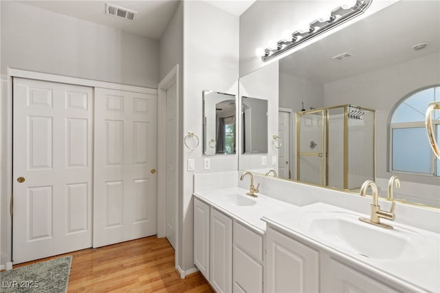 full bath with visible vents, wood finished floors, a stall shower, and a sink