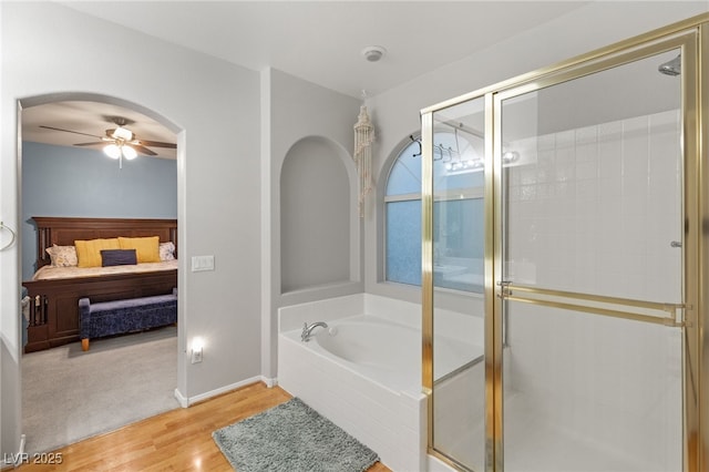 ensuite bathroom featuring wood finished floors, ensuite bath, ceiling fan, a shower stall, and a bath