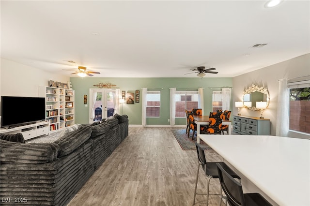 living room featuring a ceiling fan, light wood-type flooring, visible vents, baseboards, and recessed lighting