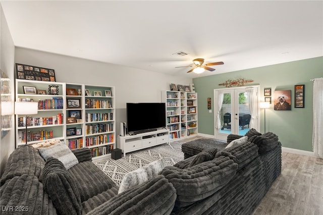 living room featuring a ceiling fan, baseboards, visible vents, and wood finished floors
