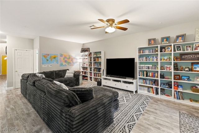 living area with a ceiling fan, visible vents, and wood finished floors