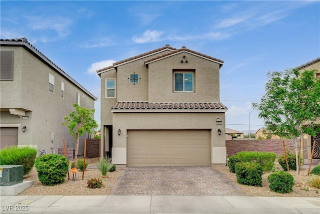 view of front of home with a tile roof, a garage, decorative driveway, fence, and stucco siding