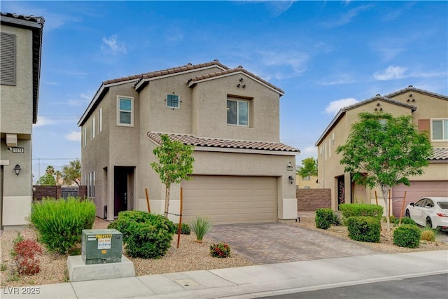 mediterranean / spanish home featuring a tiled roof, driveway, fence, an attached garage, and stucco siding