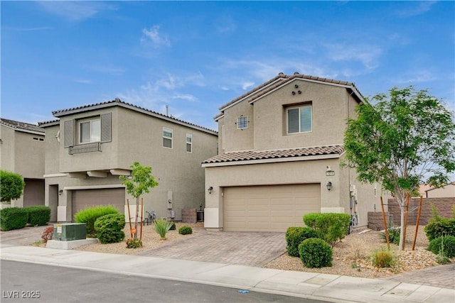 view of front facade with a tiled roof, decorative driveway, fence, an attached garage, and stucco siding