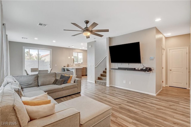 living area with light wood finished floors, stairs, a ceiling fan, baseboards, and visible vents