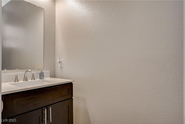 bathroom with vanity and a textured wall