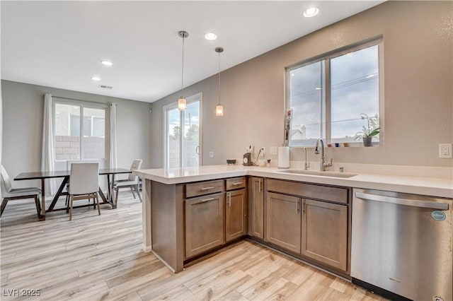 kitchen featuring dishwasher, a sink, light countertops, a peninsula, and recessed lighting