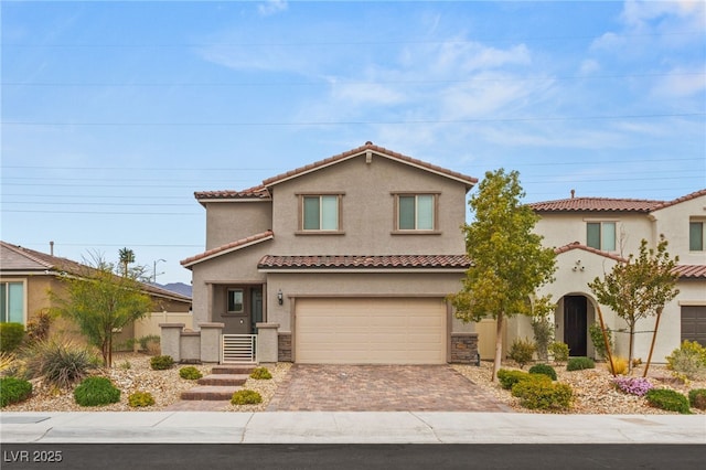 view of front of home featuring decorative driveway, an attached garage, a tile roof, and stucco siding