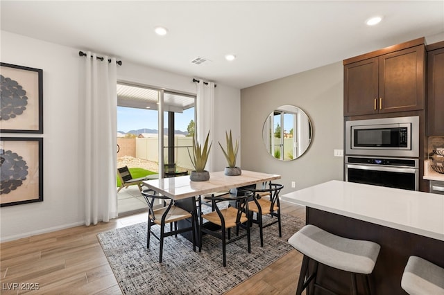 dining area with light wood-style floors, recessed lighting, and visible vents