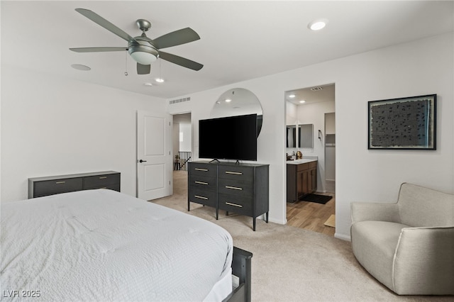 bedroom featuring visible vents, ensuite bathroom, light colored carpet, recessed lighting, and a ceiling fan