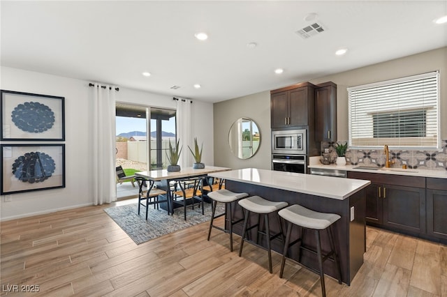 kitchen featuring a kitchen breakfast bar, a kitchen island, visible vents, a sink, and stainless steel appliances