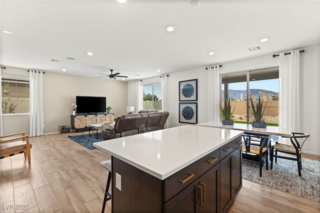 kitchen featuring a kitchen island, a ceiling fan, visible vents, light countertops, and light wood-style flooring