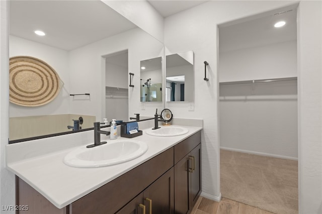 bathroom with a sink, double vanity, and a spacious closet