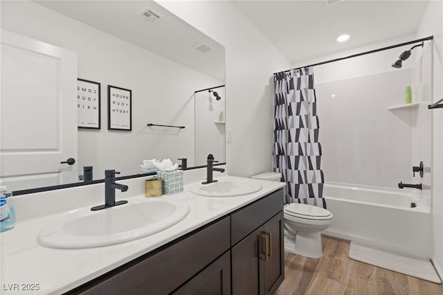 full bath featuring double vanity, toilet, a sink, and wood finished floors