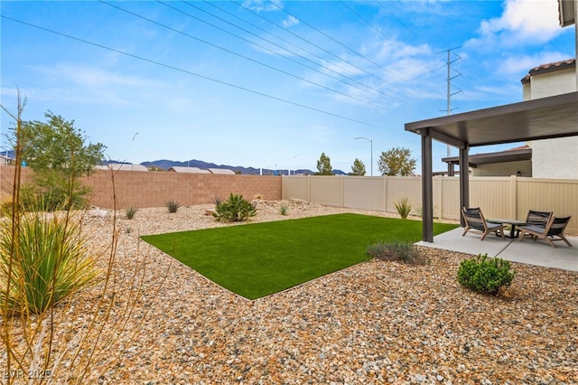 view of yard with a patio, a fenced backyard, and a mountain view