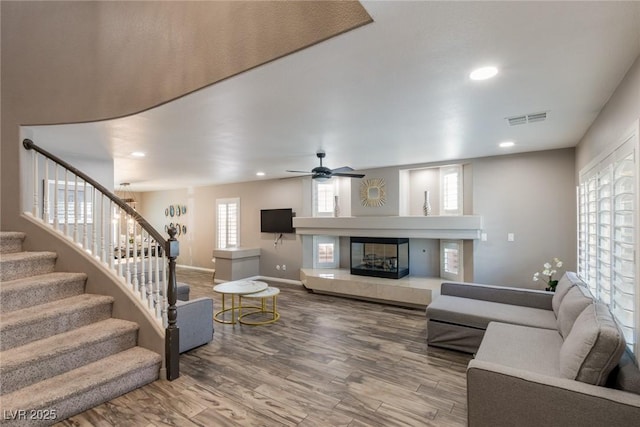 living area with visible vents, stairs, wood finished floors, baseboards, and recessed lighting