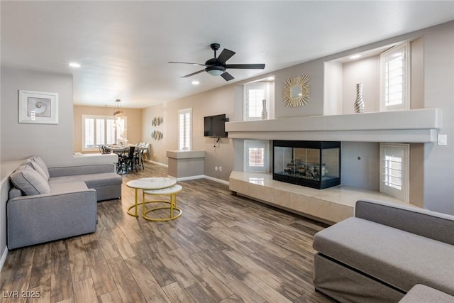 living room with baseboards, a ceiling fan, wood finished floors, and a tile fireplace