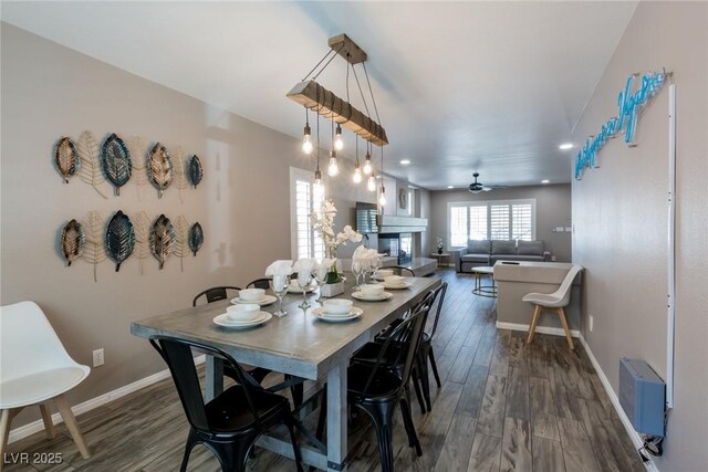 dining area featuring a ceiling fan, dark wood-style flooring, baseboards, a glass covered fireplace, and recessed lighting