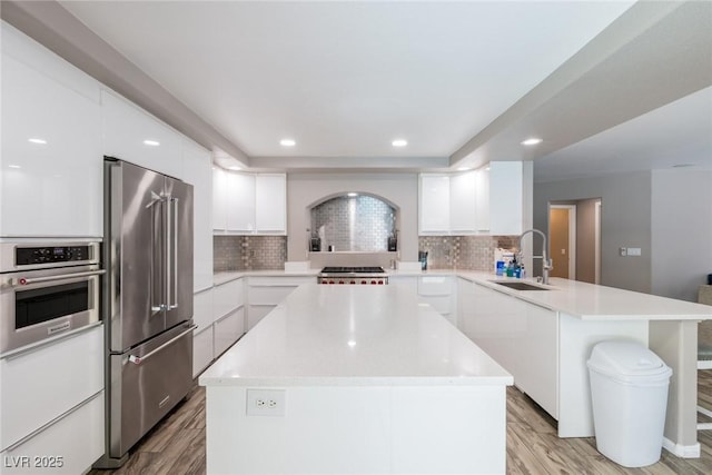 kitchen with a sink, appliances with stainless steel finishes, modern cabinets, and a peninsula