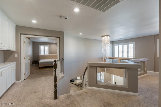 hall featuring visible vents, recessed lighting, an upstairs landing, and light colored carpet