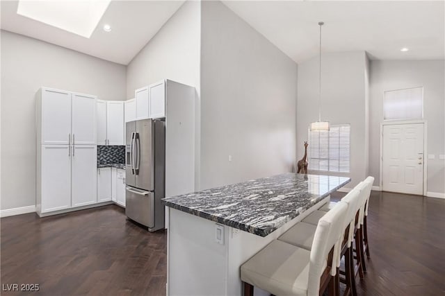 1084 Little House Ct, Henderson, NV 89011 - kitchen with dark stone counters, stainless steel fridge with ice dispenser, a breakfast bar area, and dark wood finished floors