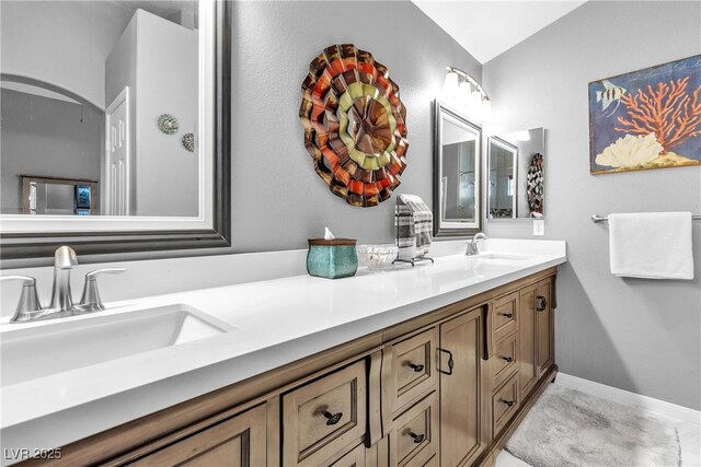 full bath featuring double vanity, a sink, and vaulted ceiling