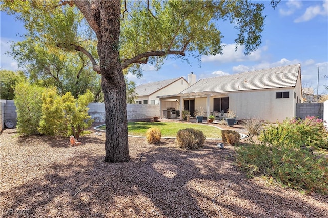 back of house featuring stucco siding, fence, a yard, and a tiled roof
